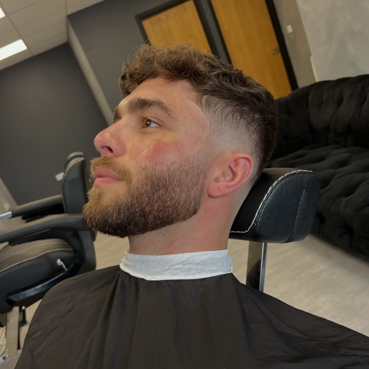 Curly textured crop with mid skin fade and blended beard — barber cut at STANDRD, Leamington Spa